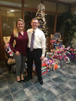 Jason and Allison Jones near the Christmas Tree with Toys for Tots collection around it