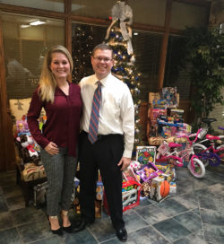 Jason and Allison Jones near the Christmas Tree with Toys for Tots collection around it